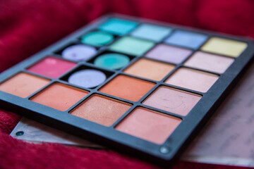 Closeup of eye shadow palettes in various colors on a red background