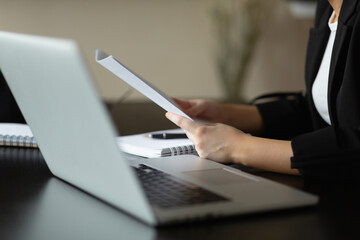 Caucasian woman holds a document in her hands. Close-up plan. Workplace in the office.