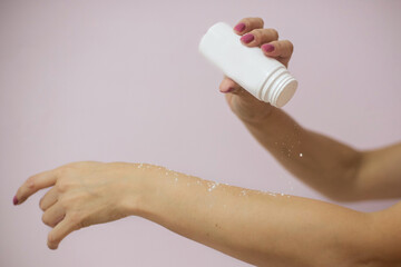 Hands of women's hands hold a white jar with powder from which a white powder is poured