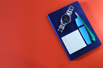 Felt-tip pen, blue diary, wristwatch, self-adhesive stickers, pen on a yellow background with space for text. Office work concept with space for text. Business