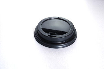 Black plastic disposable top cover for paper cups marked with processing, hot and food pictograms, isolated on white.