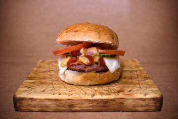 Cheeseburger, tomato and pickles, on a cutting board.