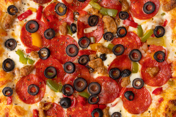 Italian pepperoni pizza closeup, macro, olives, salami sausage, cheese and vegetables. Texture and background