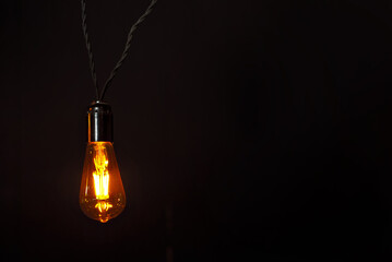 Yellow light bulb on a black background. Space for text and design layout. Copy space near light bulb. Mockup