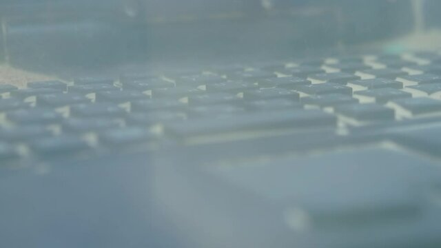 Keyboard of dustproof rugged laptop computer for military, outdoor and industrial use during dust resistance test - sand storm - close up view. Protective, resistant, safety, technology concept