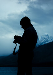 silhouette of a man with a camera in the cold mountainous region of Himalayas, Pangong Lake, Ladakh, India.