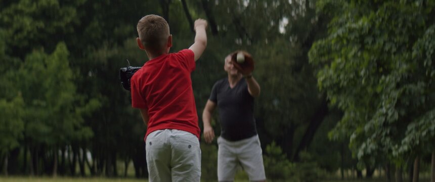 MED Father And Son Playing Baseball Catch In The Park On A Rainy Day. Family Time Spent Together. Shot With 2x Anamorphic Lens