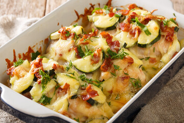 Tasty chicken baked gratin with zucchini, bacon and cheese close-up in a baking dish on the table. horizontal