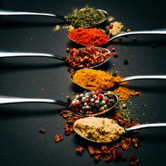 spices on a metal spoon on a black background