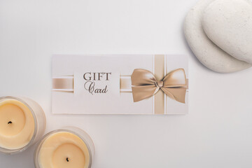 Top view of gift card near candles and zen stones on white background