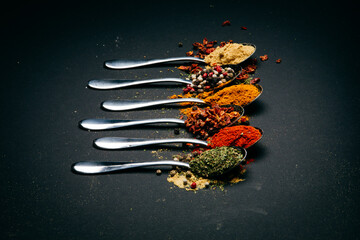 spices on a metal spoon on a black background