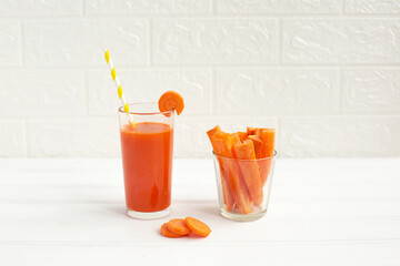 Glass of carrot juice and fresh carrot on cutting board