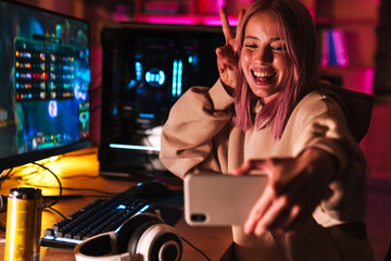 Image of girl taking selfie on cellphone while playing video game © Drobot Dean