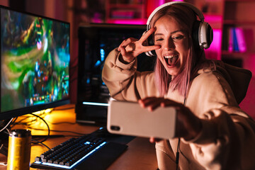 Image of girl taking selfie on cellphone while playing video game