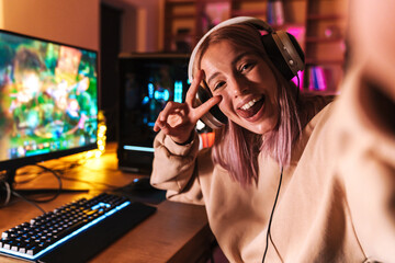 Image of excited girl taking selfie photo while playing video game