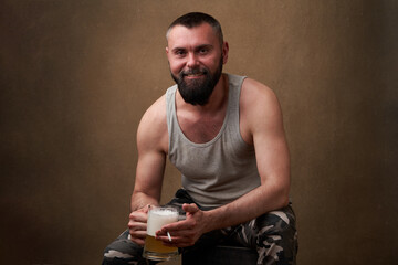 Portrait of a handsome man with a beard holding a mug of beer