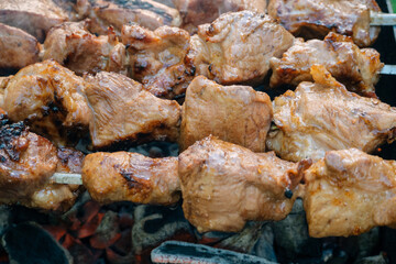 barbecue pork meat on skewers on fire on the grill