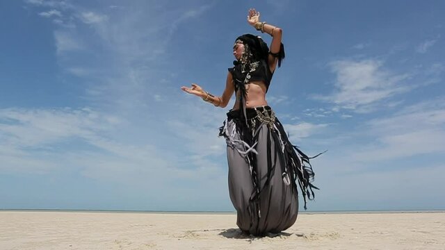 Beautiful young stylish tribal dancer. Woman in oriental costume dancing outdoors
