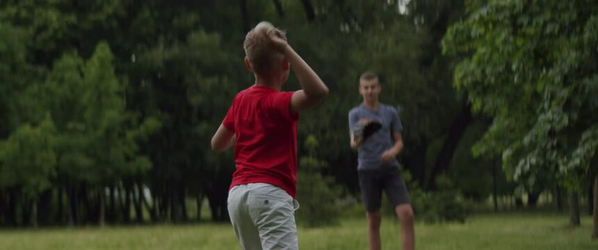 MED Two brothers or friends playing baseball catch in the park. Family time spent together. Shot with 2x Anamorphic lens