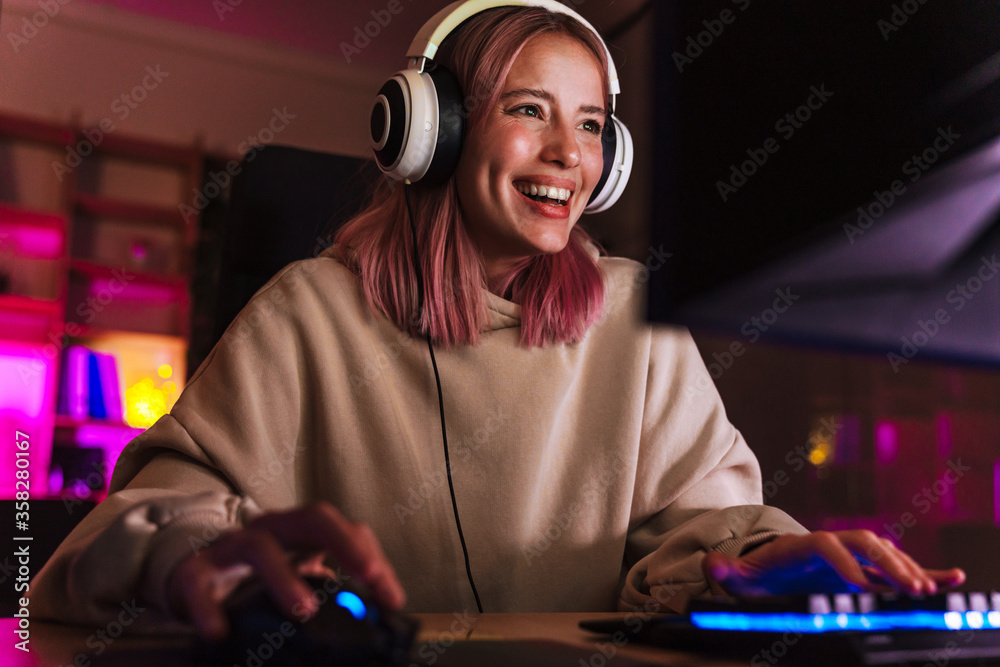 Wall mural image of joyful girl smiling and playing video game on computer