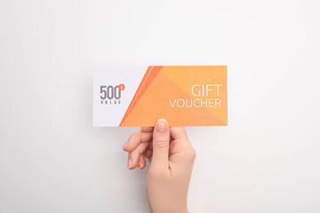 Top view of woman holding gift voucher with 500 value lettering on white background - obrazy, fototapety, plakaty