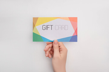 Top view of woman holding colorful gift card on white background
