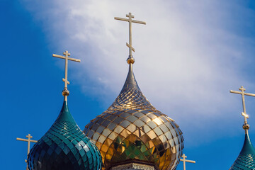 Golden shiny and green domes with crosses on Christian Orthodox Church