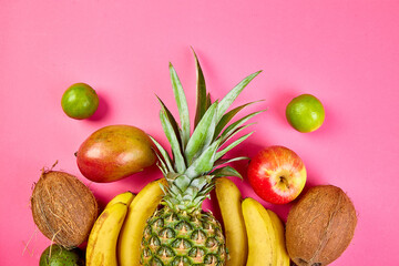 Flat lay of exotic fruits on pink background.