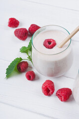 Glass of raspberry milkshake on wooden background