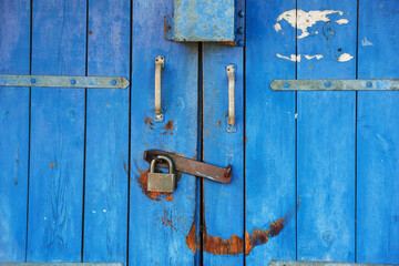 Old retro vintage weathered blue door with rusted metal lock