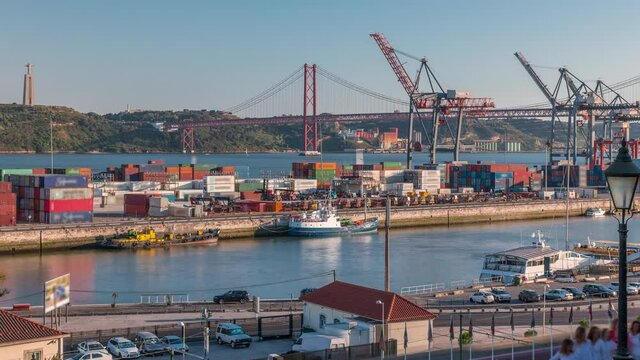 Skyline over Lisbon commercial port timelapse, 25th April Bridge, containers on pier with freight cranes, city train Lisbon, Portugal. Aerial view before sunset