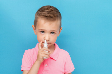 Portrait of a kid with anti-allergic nosal spray on a blue background