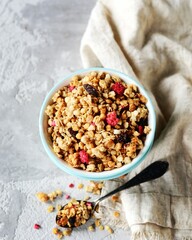 Homemade granola with berries and nuts in a bowl on a gray background
