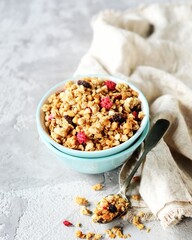 Homemade granola with berries and nuts in a bowl on a gray background