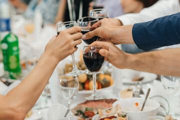hands of a group of friends clinking glasses of wine and toasting