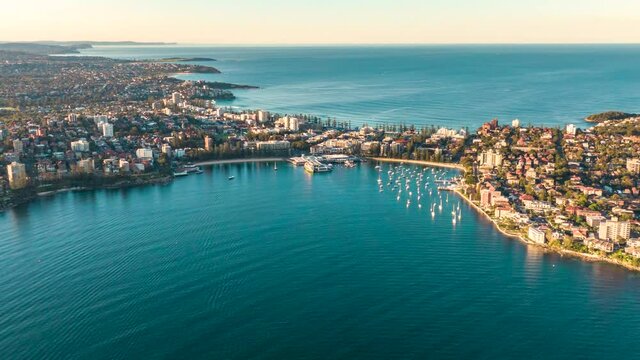 Sunset aerial drone hyperlapse of ferries arriving from Sydney CBD (Circular Quay), docking at Manly Wharf pier - a 20 minute ride from the city. Manly is a beach-side suburb of Sydney, Australia.