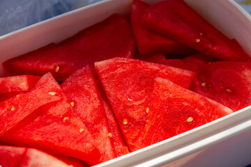 Red, juicy sliced ​​watermelon lies in a plastic box.