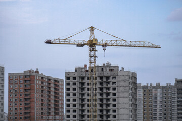 Fototapeta premium Multi-stage construction during the construction process with a yellow crane. Industrial background for design.