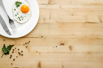 Fried eggs on plate - light wooden background top-down copy space