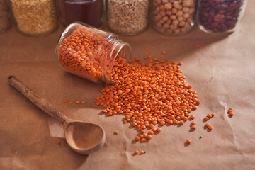 red lentils with wooden spoon close-up. Against the background of a jar with other cereals. Superfood