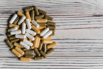  sprinkled pills and dietary supplements on a wooden background, vitamins and omega3 for immunity
