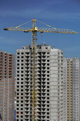 Multi-stage construction during the construction process with a yellow crane. Industrial background for design.