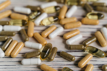  sprinkled pills and dietary supplements on a wooden background, vitamins and omega3 for immunity