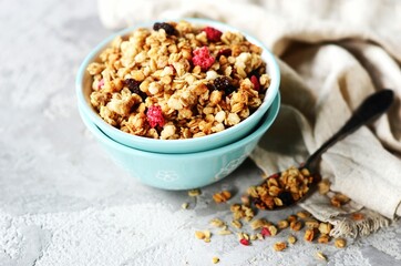 Homemade granola with berries and nuts in a bowl on a gray background