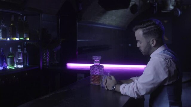 chico en la barra de un club con ne&oacute;n morado