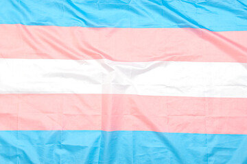 Transgender fabric flag with white, pink, blue strips. Close-up transgender pride flag as background or texture