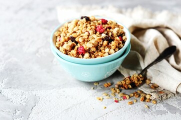 Homemade granola with berries and nuts in a bowl on a gray background