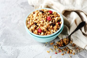 Homemade granola with berries and nuts in a bowl on a gray background