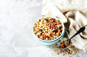 Homemade granola with berries and nuts in a bowl on a gray background