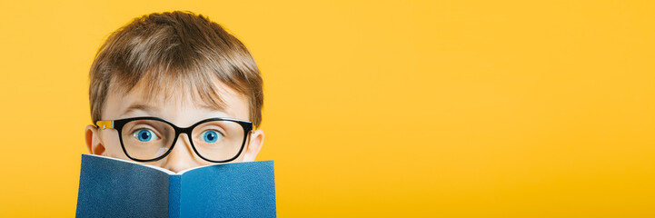 child reads a book against a bright wall